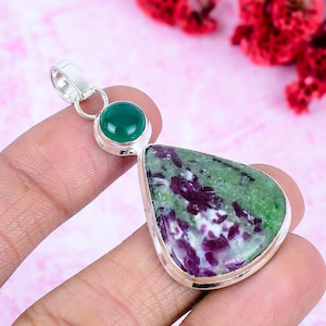 Può includere: Un ciondolo in argento con una pietra a forma di pera verde e viola incastonata in una cornice di metallo liscio, sormontata da una pietra rotonda verde più piccola in un'incastonatura d'argento abbinata. Il ciondolo ha un gancio in argento.