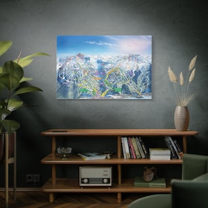 May include: A detailed ski resort map print, depicting mountain trails and elevations. The artwork features a colorful illustration of the ski slopes, with vibrant hues highlighting the different runs. The print is displayed on a wall, adding a decorative touch to the room.