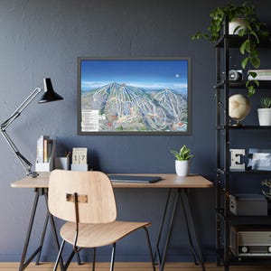 May include: A framed print of a ski resort map, showcasing the mountain's trails and features. The print is displayed on a dark blue wall above a wooden desk. A black desk lamp and a wooden chair are positioned near the desk. The scene is complemented by a black shelving unit with plants.