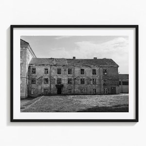 Puede incluir: Una fotografía en blanco y negro de un edificio abandonado con múltiples ventanas. El edificio tiene una fachada desgastada y un techo de tejas. El edificio está rodeado de una zona de césped.