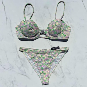 May include: A white ceramic mug with a black handle and the text "But First, Coffee" in a handwritten style. The mug is on a white surface. The mug is approximately 4 inches tall.