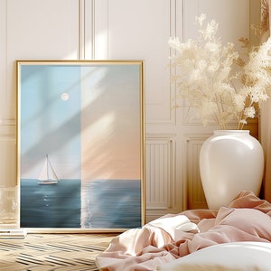 May include: A framed painting of a sailboat on the ocean with a full moon in the sky. The painting is in a gold frame and is hanging on a white wall. The wall is paneled and has a white trim. There is a vase of dried flowers in the foreground.