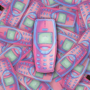 May include: A collection of pink and blue retro cell phone illustrations. The phones have a screen that reads "CUTIE" and "MENU". The phones are a mix of pink and blue with a retro aesthetic.