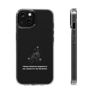 Peut inclure: Coque de téléphone transparente avec un dos noir texturé. La coque présente un dessin au trait blanc de mains et de cristaux, avec le texte "I know whatever happens to me, I know it's for the better."
