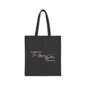 May include: Black tote bag with white text and a line drawing of two hands reaching towards each other. The text reads "he is half of my soul as the poets say."