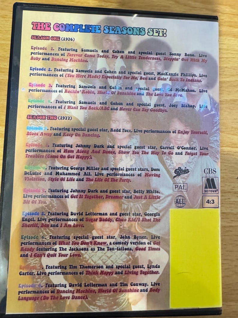 Puede incluir: Una caja de DVD con un fondo hologr&aacute;fico azul y morado que presenta una foto de un grupo de personas. La caja enumera las temporadas completas de un programa de televisi&oacute;n, "The Complete Seasons Set!" con las temporadas y los episodios enumerados. La caja tambi&eacute;n incluye el logotipo del programa, "CBS", y el texto "PAL" y "4:3".
