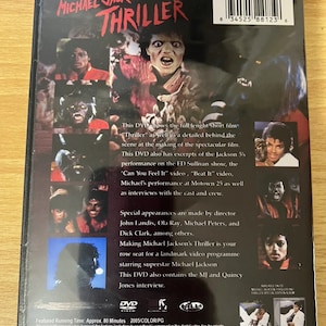 Puede incluir: La contraportada de un DVD con Michael Jackson's Thriller. La portada es negra con texto rojo y tiene un c&oacute;digo de barras. El DVD incluye el cortometraje completo "Thriller", as&iacute; como im&aacute;genes detr&aacute;s de escena, extractos de la actuaci&oacute;n de los Jackson 5 en el programa de Ed Sullivan, y entrevistas con el reparto y el equipo.
