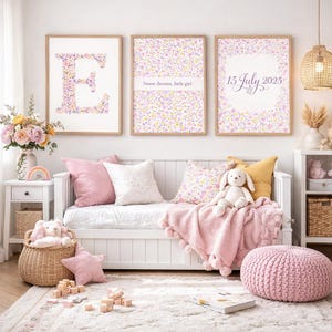 May include: A cozy nursery scene with a white daybed, pink pillows, and a soft pink blanket. Three framed floral prints hang above the bed. The prints feature the letter "E", the text "Sweet dreams, little girl", and the date "15 July 2025".
