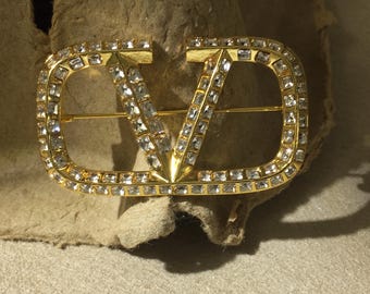 Broche vintage Valentino de doble letra con incrustaciones de diamantes de imitación en tono dorado.
