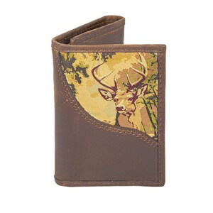 Puede incluir: Cartera de cuero marrón con escena de ciervo. La cartera presenta un exterior de cuero marrón con un panel decorativo que representa un ciervo en un entorno forestal. La cartera está abierta.