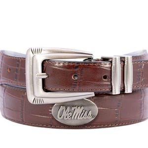 May include: A brown leather belt with a crocodile texture. The belt features a silver buckle and a silver oval emblem with the text "Ole Miss". The belt is designed for casual wear.