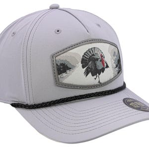 May include: A light gray baseball cap featuring a detailed embroidered patch with a turkey design. The cap has a curved brim, a black rope detail, and a button on top. The turkey is depicted in shades of gray, red, and white.