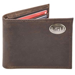 Puede incluir: Cartera de cuero marrón con las letras "LSU" en un óvalo plateado. La cartera está abierta, revelando ranuras para tarjetas con tarjetas rojas y negras visibles. La costura es visible alrededor de los bordes.