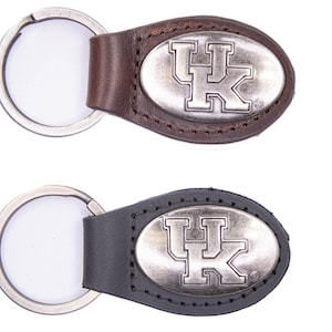 May include: Two keychains with oval leather tags and silver key rings. One keychain has a brown leather tag, the other a black leather tag. Each tag features a silver emblem with the letters "UK".