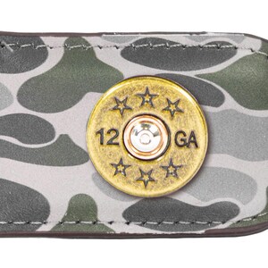 May include: A camouflage patterned leather money clip with a gold-toned 12 GA bullet casing design.