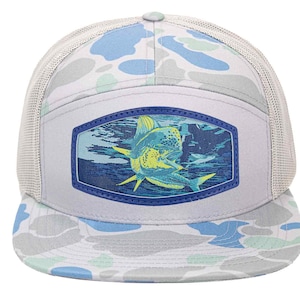 May include: A light grey trucker cap with a camouflage pattern in blue, white, and green. The front panel has a rectangular patch with a blue border, showing a detailed illustration of a fish underwater.