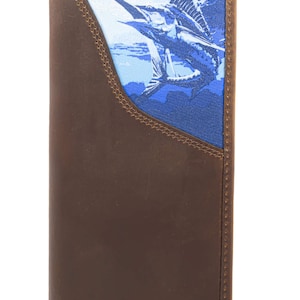 Puede incluir: Cartera de cuero marrón con un diseño de pez vela azul y blanco. La cartera tiene un borde cosido y un diseño vertical. El pez vela se representa nadando bajo el agua. La cartera es de estilo bi-fold.
