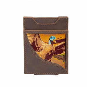 Puede incluir: Tarjetero de cuero marrón con una imagen bordada de un pato en vuelo. El pato tiene plumas azules, marrones y amarillas. El tarjetero tiene forma rectangular con la parte superior curvada y un bolsillo frontal.