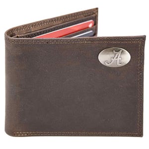 Puede incluir: Una cartera de cuero marrón con un emblema ovalado plateado con una "A" en escritura. La cartera está abierta, revelando ranuras para tarjetas con tarjetas visibles. La cartera es rectangular con bordes cosidos.