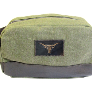 Peut inclure: Sac de voyage en toile verte avec une garniture en cuir marron et un patch en cuir marron avec un logo de tête de Longhorn doré.
