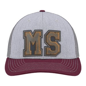 May include: A baseball cap featuring a heather grey front panel and a maroon brim with white stitching. The front displays the letters MS in a large, block-style font with a dark brown, textured finish and a stitched border on the grey fabric.