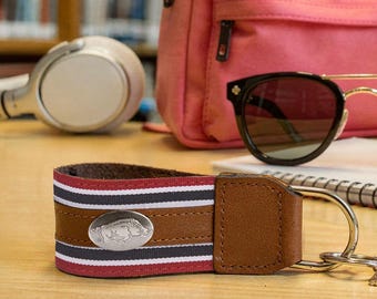 Llavero con cinta de grosgrain universitaria de Arkansas Razorbacks con detalle de cuero y emblema plateado.