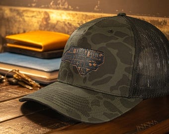 North Carolina Map Old School Camo Trucker Hat. Burnished Full Grain Leather Patch. 5-Panel Richardson 112 Snapback Cap. Stitched Map Patch.