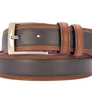 May include: A brown and black leather belt with a silver buckle. The belt has a dark brown center with lighter brown edges and accents. The belt is approximately 1.5 inches wide.