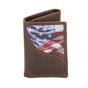 Puede incluir: Cartera de cuero marrón con un diseño de la bandera estadounidense. La cartera presenta un exterior marrón con un panel de tela que muestra las estrellas y las rayas de la bandera estadounidense. La cartera está abierta, revelando el interior.