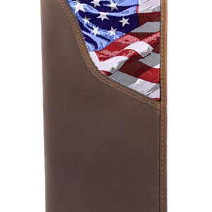 Puede incluir: Cartera de cuero marrón con un diseño de la bandera estadounidense en el interior. La cartera es rectangular y tiene un diseño de dos pliegues. La bandera presenta rayas rojas y blancas con un campo azul de estrellas blancas.