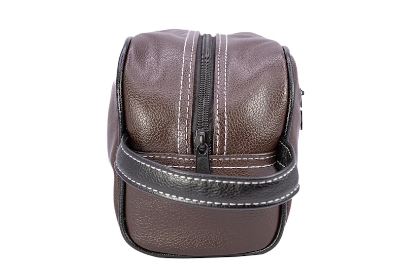 Puede incluir: Neceser de cuero marr&oacute;n con cremallera y asa negras. La bolsa tiene costuras blancas y un ribete negro. Dise&ntilde;ado para guardar art&iacute;culos de aseo y objetos personales.