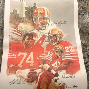 May include: A vintage San Francisco 49ers football poster featuring four players in red and gold uniforms. The poster is signed by Joe Montana, Dwight Hicks, Ronnie Lott, and  Jeff  Dean. The poster also features the San Francisco skyline in the background.