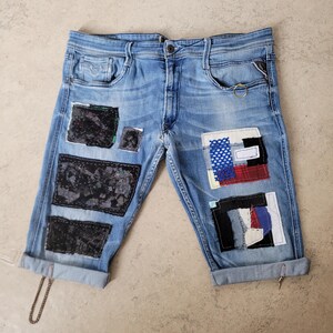 May include: Blue denim shorts with multiple patches of different fabrics and colours, including black, white, red, and blue. The patches are sewn on in a patchwork style.