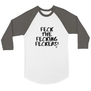 May include: White and gray raglan baseball shirt with the text "FECK THE FECKING FECKERS!" in black, handwritten-style font. The shirt has a crew neck and three-quarter length sleeves.