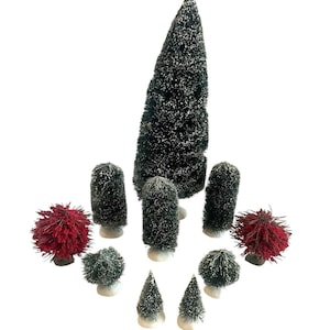 Puede incluir: Una colección de árboles de Navidad en miniatura de varias formas y tamaños. Los árboles son principalmente de color verde oscuro con un poco de blanco, algunos con un aspecto rojo y puntiagudo. Cada árbol está montado sobre una base blanca.