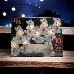 Könnte beinhalten: Eine Schachtel mit 10 weißen, geisterförmigen LED-Lichterketten mit roter Zunge und gelbem Licht im Inneren. Die Schachtel trägt die Aufschrift "Trick or Treat" und "Ghost Stack Light Set" mit einem UL Listed-Label. Die Lichter sind 8 Fuß lang und können drinnen oder draußen verwendet werden.