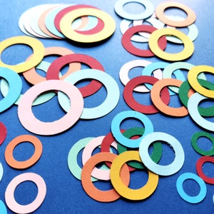 May include: Assortment of colorful paper circles in various sizes, arranged on a blue background. The circles are cut from different colored paper, including red, yellow, blue, green, and pink.