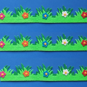 Puede incluir: Tres filas de hierba verde de fieltro con flores de fieltro de colores. Cada fila tiene seis flores en los colores rosa, naranja, azul, blanco, rojo y naranja.