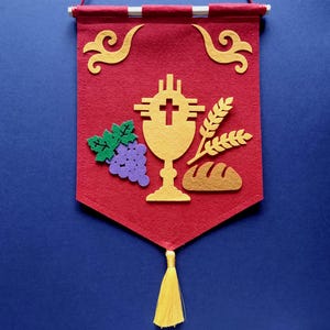 Könnte beinhalten: Ein rotes Filzbanner mit einem goldenen Kelch, Trauben, Brot und Weizenähren. Das Banner hat einen goldenen Quasten und ist mit goldenen Schnörkeln verziert.