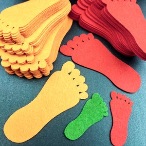 May include: A collection of die-cut felt shapes in the form of human footprints. The set includes multiple stacks and individual pieces in vibrant orange, bright red, and lime green colors, featuring distinct toe and heel outlines.