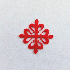May include: A red felt cross with a decorative design. The cross is a traditional symbol of faith and is often used in religious art and crafts.