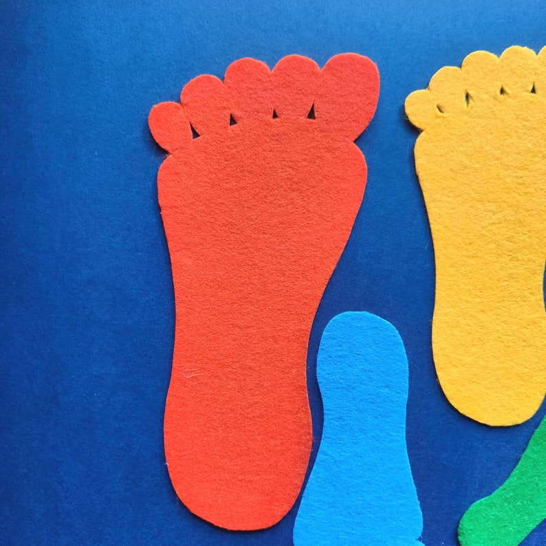May include: A collection of felt cutouts shaped like human footprints in various colors including red, yellow, blue, and green. The shapes feature distinct toe and heel sections, arranged in a scattered pattern against a solid blue background.