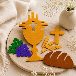 May include: A set of felt cutouts featuring a mustard yellow chalice with a cross cutout, a mustard yellow cross, a cluster of purple grapes with green leaves, three mustard yellow wheat stalks, and a brown loaf of bread on a wooden board.
