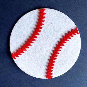 Könnte beinhalten: Weißer Filz-Kreis mit roten Filz-Nähten in Form eines Baseballs.