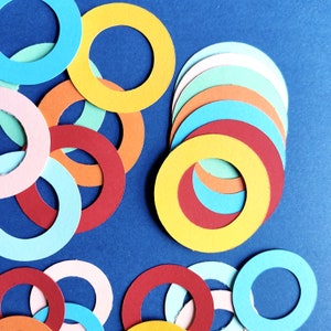 May include: A collection of colorful paper circles in various sizes and shades of blue, red, yellow, and green. The circles are arranged in a random pattern on a dark blue background.