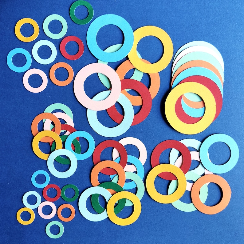 May include: A collection of colorful paper circles in various sizes and shades of red, blue, yellow, and green. The circles are arranged in a random pattern on a blue background.