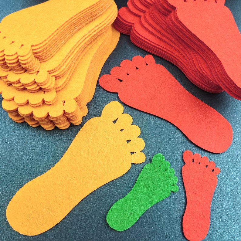 May include: A collection of die-cut felt shapes in the form of human footprints. The set includes multiple stacks and individual pieces in vibrant orange, bright red, and lime green colors, featuring five distinct toe shapes on each cutout.