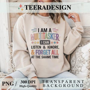 Puede incluir: Una sudadera beige con el texto "I AM A MULTITASKER" en letras coloridas. El diseño incluye las frases "I CAN LISTEN & IGNORE, & FORGET ALL AT THE SAAME TIME". La imagen también incluye el texto "PNG / 300 DPI High-Quality TRANSPARENT BACKGROUND".