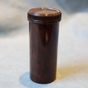 Op de afbeelding: Een bruine plastic container met een houtnerfpatroon en een schroefdop.