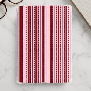 May include: A rectangular tablet case featuring a repeating vertical pattern of dark red scalloped stripes separated by thin solid dark red lines against a light pink background. The case has a clear, transparent protective border edge.